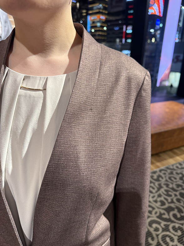 優しいベージュが特徴のノーカラースーツ